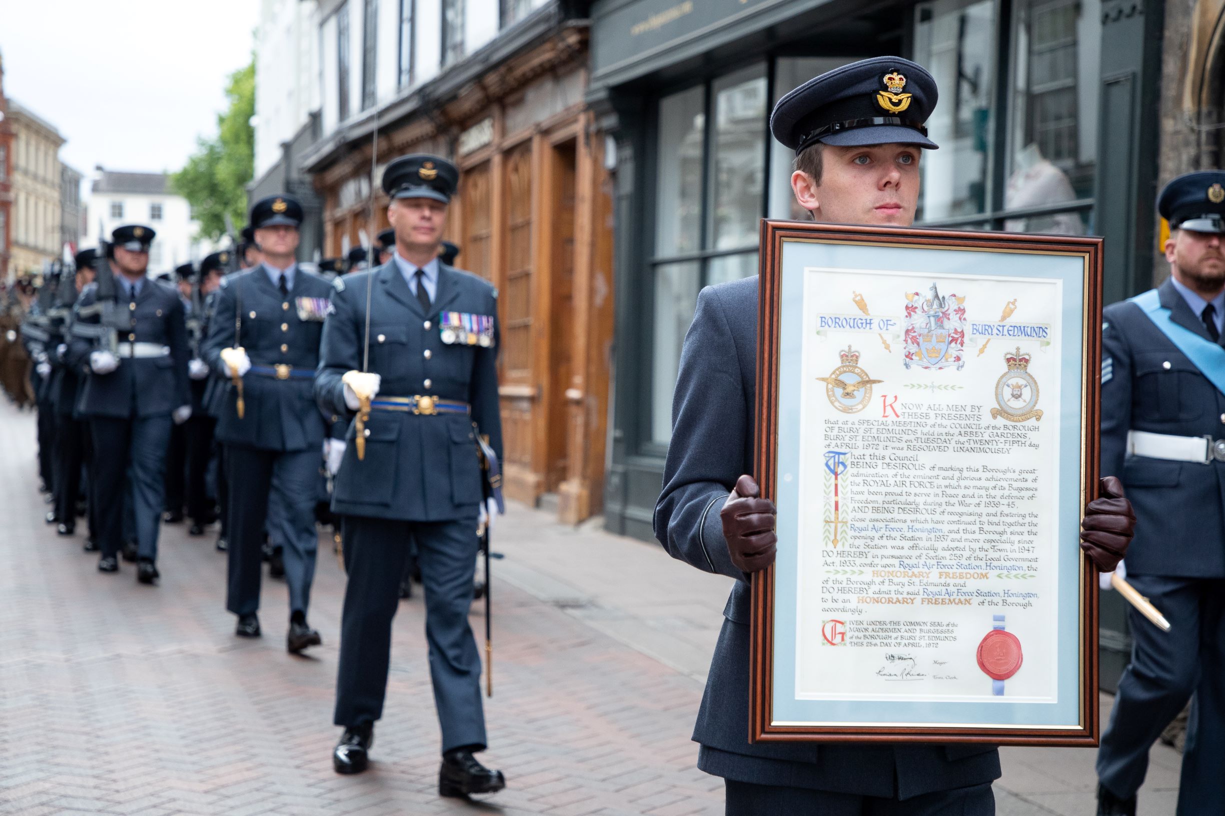 RAF Aviators parade through streets, with framed certificate of award.